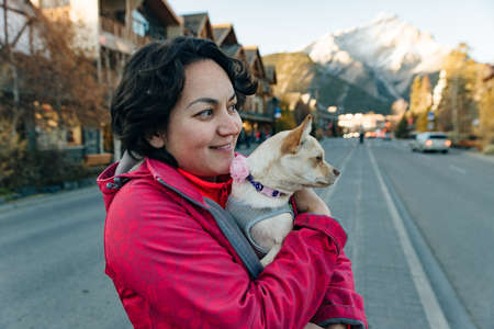 girl in an red jacket holds a chihuahua in her arms near lake, canada - dec, 2019.のeditorial素材