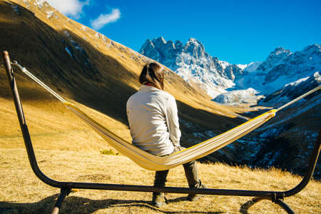 The girl lies on a hammock in the background of the mountains. Caucasus Mountains in Georgia