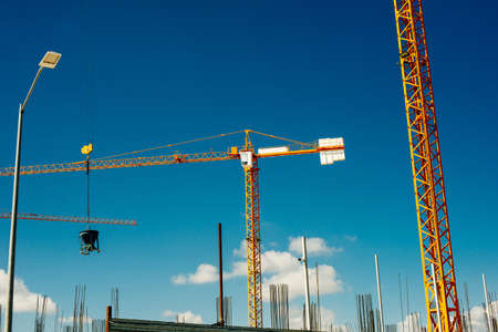 Yellow Industrial Cranes Working on Construction Site Against Blue Sky.の写真素材