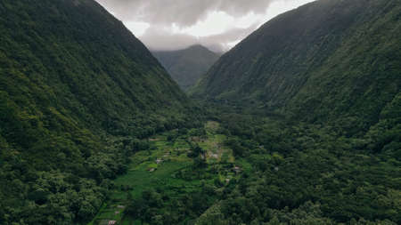 Aerial view of the Waipio Valley on the Big Island of Hawaii with its beautiful waterfalls shrouded in fog and clouds.の写真素材