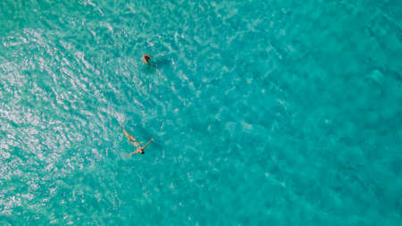 Couple of woman floating in clear blue ocean. Aerial view. High quality photoの写真素材