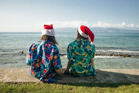 girls in hawaiian shirts sit on the beach at christmas in hawaii. High quality photoの写真素材