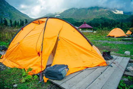 Orange tourist tent on a hill above the ravine. tent stands in the thick green grass at sunset. Summer landscapeの写真素材