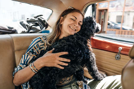 Woman and dog in car on summer travel. Funny dog traveling. Vacation with pet concept. High quality...