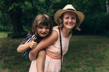Young mother carrying child on her back. Woman walking in the mountains with son. High quality photoのeditorial素材
