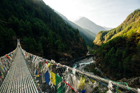 Suspension bridge with buddhist prayer flags on the Annapurna circuit trek in Nepal. High quality...