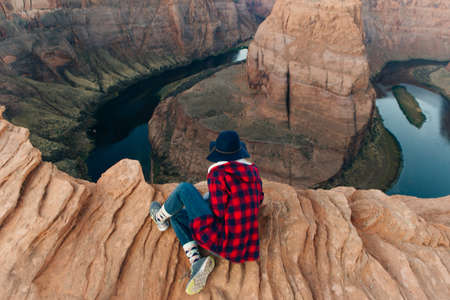 blonde girl sitting Horseshoe Bend in Glen Canyon National Recreation Area in early dawn.の写真素材