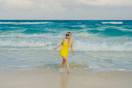 beautiful blonde in sunglasses in a yellow dress on a background of the ocean. Caribbean Coast,...