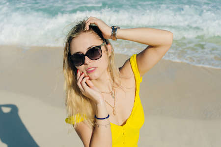 beautiful blonde in sunglasses in a yellow dress on a background of the ocean. Caribbean Coast,...
