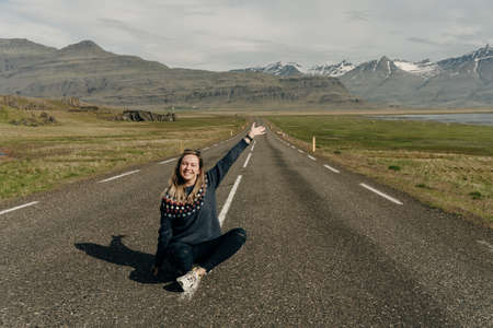 girl sitting on the road against the backdrop of Icelandic landscapes. high quality photoの写真素材