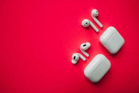 White headphones with wireless charging case. New ear pods 2019-2020 on black background. Female and...