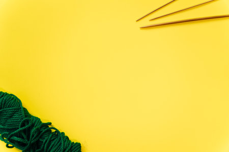 white wool knitting needles and a piece of knitting against a yellow background. high quality photoの写真素材