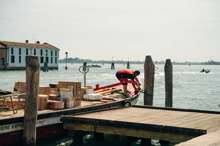 a worker unloads a boat with boxes. Venice, Milan - May 2023. High quality photo