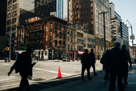 Busy street scene in New York City with groups of people walking across a crowded intersection on...