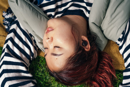 Asian girl listens to music lying on the grass. High quality photo