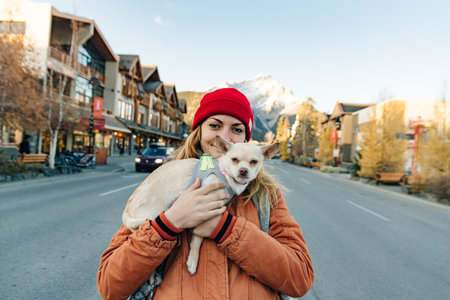 girl in an orange jacket holds a chihuahua in her arms near lake, canada.の写真素材