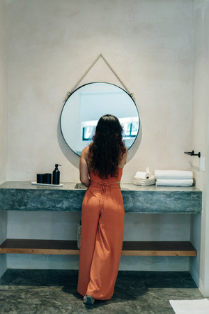 The girl stands with her back to the mirror.の写真素材