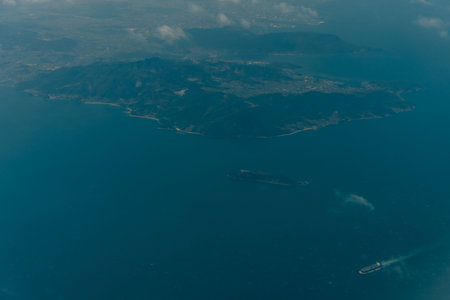 Aerial view through the clouds to the sea bay with coastal hills. Top view from the clouds to Japan islands. High quality photoの写真素材
