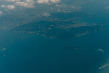 Aerial view through the clouds to the sea bay with coastal hills. Top view from the clouds to Japan islands. High quality photoの写真素材
