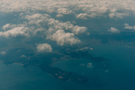 Aerial view through the clouds to the sea bay with coastal hills. Top view from the clouds to Japan islands. High quality photoの写真素材