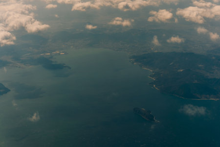 Aerial view through the clouds to the sea bay with coastal hills. Top view from the clouds to Japan...