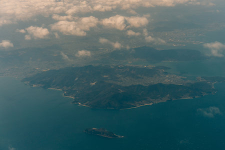 Aerial view through the clouds to the sea bay with coastal hills. Top view from the clouds to Japan islands. High quality photoの写真素材