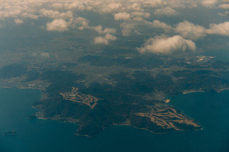 Aerial view through the clouds to the sea bay with coastal hills. Top view from the clouds to Japan...