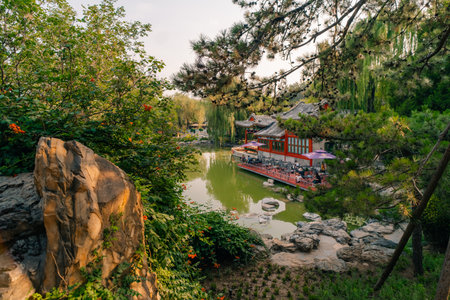 Ornate pavilion mirrored in a lake of the historical Ritan Park which means Park of the Sun, Beijing, Chinaの写真素材