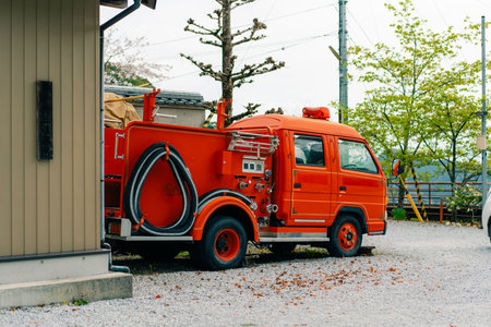 A large, red fire engine is parked sideways near a building in Japan. High quality photoの写真素材