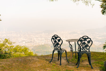 shikoku, japan - 3 August 2025 wrought iron garden furniture, consisting of two chairs and a round table, located on a hill overlooking the city. High quality photoの写真素材