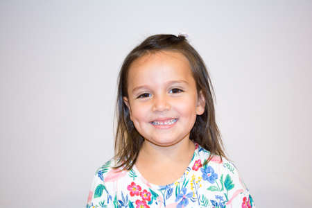 Portrait of a five year old girl making funny faces & wearing a dress with a floral patternの写真素材
