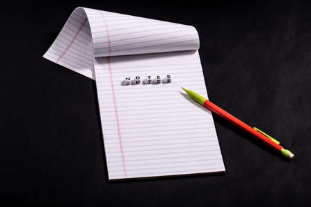 Note Pad on Black background with bright mechanical pencil and word notesの写真素材