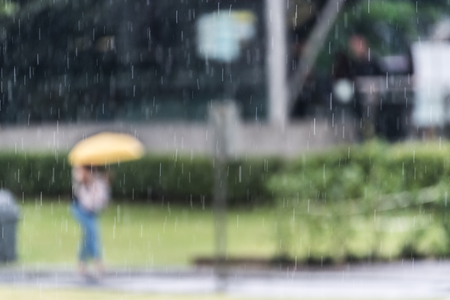 Woman walking down the street in rainy day. Intentional motion blur