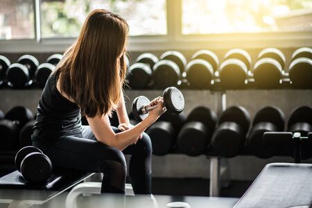 Fitness woman in training exercises with dumbbells.の写真素材