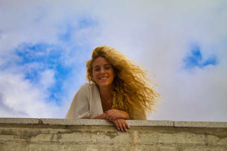 blonde girl leaning out of the park wallの写真素材