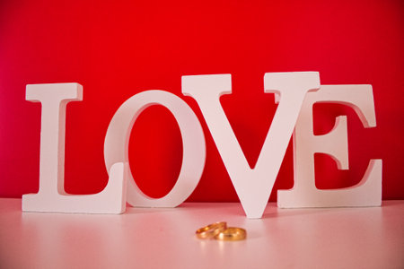 gold wedding rings on a white background and white love letters on a red backgroundの写真素材