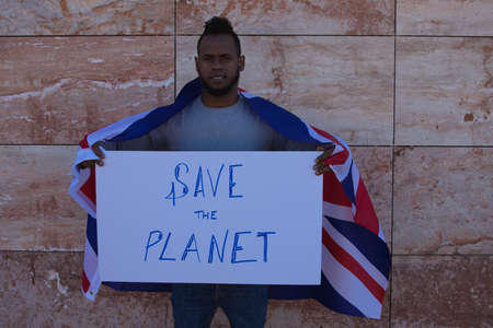 An African-american man on a wall holds a sign that reads stop racism. The man is carrying a German flag on his shoulders.の写真素材