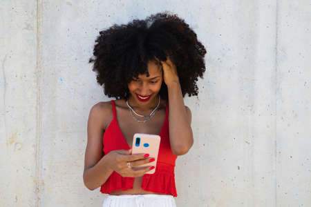 beautiful afro american woman smiling and looking at the camera doing different poses and gestures with her face. The woman is wearing a red top and red lipstick. Concept happinessの写真素材