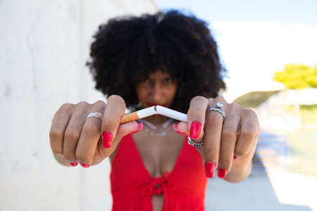 beautiful afro american woman breaking a cigarette and looking at the camera. Campaign on smoking cessation awareness. Health concept. Smoke-free worldの写真素材