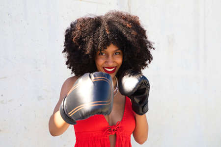 Beautiful Afro-American woman with boxing gloves claiming women's rights against mistreatment and breast cancer. Concept of women's rights.の写真素材