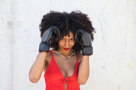 Beautiful Afro-American woman with boxing gloves claiming women's rights against mistreatment and breast cancer. Concept of women's rights.の写真素材