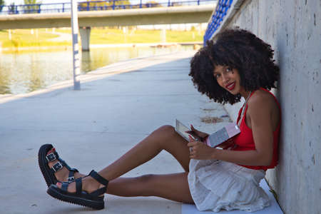 beautiful afro-american woman sitting with her laptop in a park. The photo is taken from above and you can see the girl below. Concept college studentの写真素材