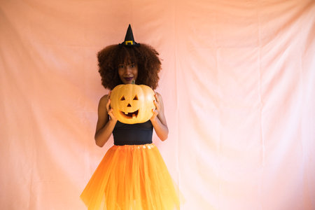 young african american woman dressed as a witch for halloween party. She wears a witch hat and orange skirt.の写真素材