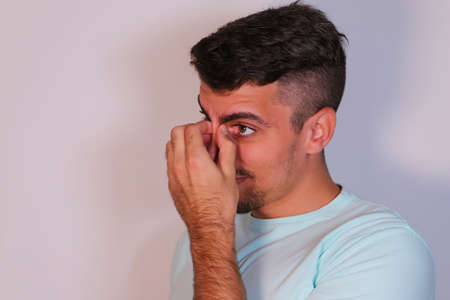 young man on a white background with an angry look on his face and looking at the camera with his fist raised in a threatening mannerの写真素材
