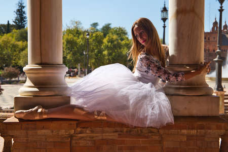 Classical ballet dancer in white tutu dancing and holding on to two white marble columns. The woman flirts with the columns while dancing. Dance conceptの写真素材
