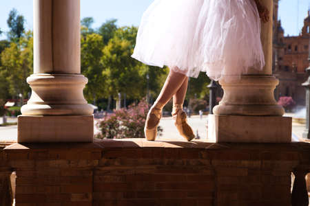 Classical ballet dancer dancing between two white marble columns. She is wearing a white tutu and the photo is backlit. The photo is spectacular.の写真素材