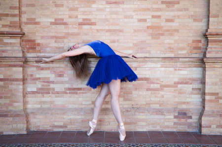 classical ballet dancer with turkey blue tutu doing different poses and postures on a background of red bricks. Classical ballet concept.の写真素材