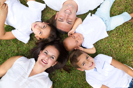 portrait of a family of five, father, mother and children lying on the fresh grass looking at the camera. It is an example of a happy and united family. Family concept parents and children.の写真素材