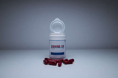 A white bottle of covid-19 antiviral pills opened and with the pills out of the bottle on the laboratory bench. Concept of the new antiretroviral treatment pill Covid-19.の写真素材