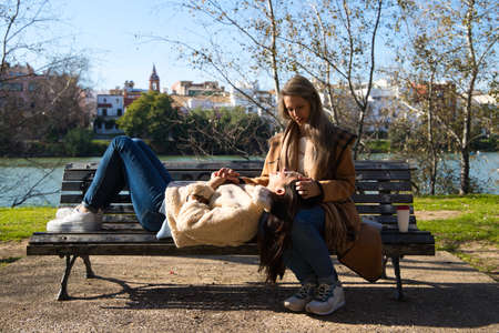 A lesbian couple on a bench by a river. One woman is sitting and the other is lying on her legs. The women are young and newly married. Concept lgtb, gays and lesbians. Rights and equalityの写真素材